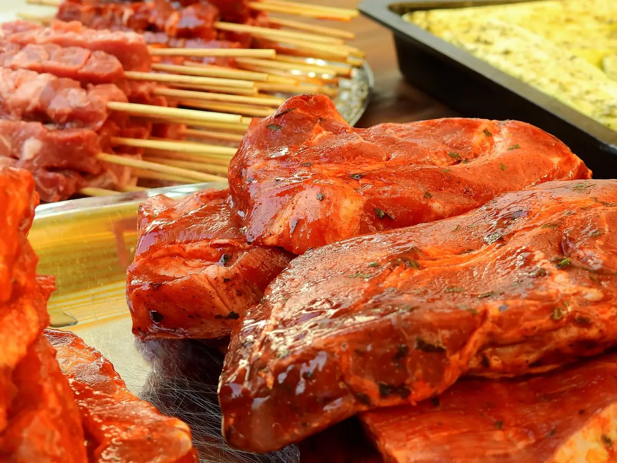 Marinated meat steaks and kebab skewers in a dark herb marinade, ready for the grill