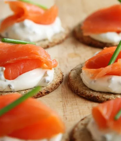 Smoked salmon and cream cheese on round crackers with chives, similar to this salmon dip recipe served as an appetizer