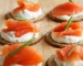 Smoked salmon and cream cheese on round crackers with chives, similar to this salmon dip recipe served as an appetizer