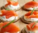 Smoked salmon and cream cheese on round crackers with chives, similar to this salmon dip recipe served as an appetizer