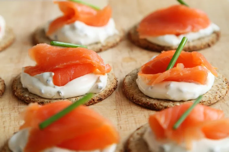 Smoked salmon and cream cheese on round crackers with chives, similar to this salmon dip recipe served as an appetizer