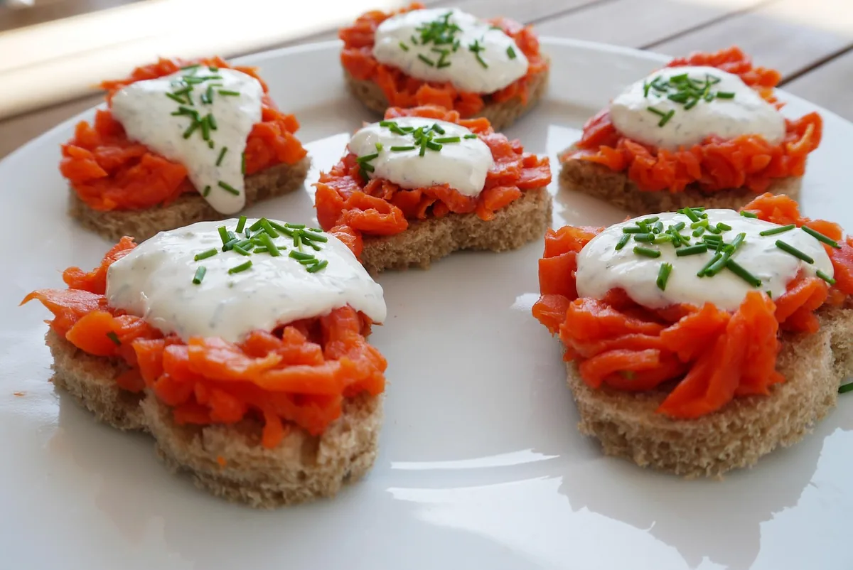 Smoked salmon on small toasts topped with a cream cheese spread and chopped chives for a party platter
