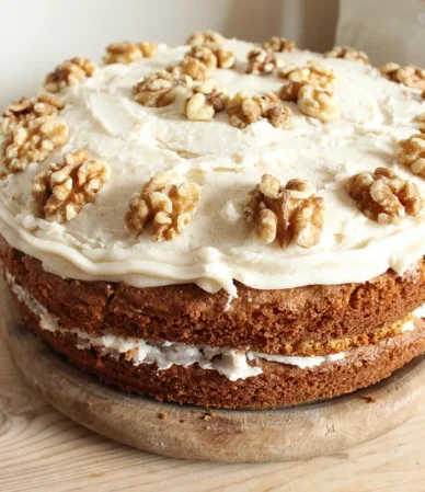 Two-layer cake with cream cheese frosting and walnut halves on a wooden board, similar to this spice cake recipe
