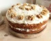 Two-layer cake with cream cheese frosting and walnut halves on a wooden board, similar to this spice cake recipe