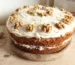 Two-layer cake with cream cheese frosting and walnut halves on a wooden board, similar to this spice cake recipe