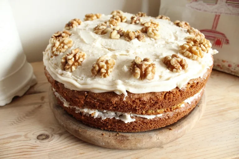 Two-layer cake with cream cheese frosting and walnut halves on a wooden board, similar to this spice cake recipe