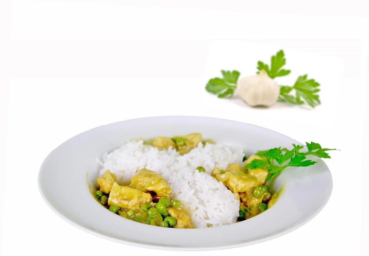 Chicken and rice with peas and parsley served on a white plate