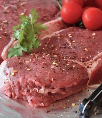 Raw beef steaks seasoned with pepper and herbs on foil, ready for a steak marinade