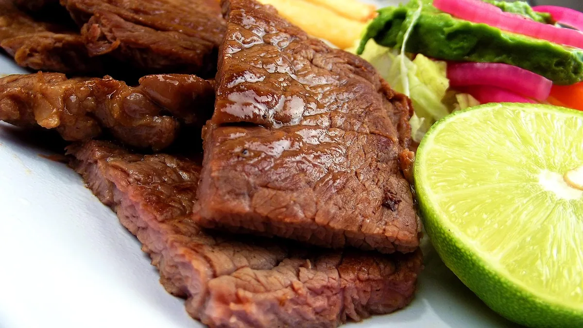 Thin grilled marinated steak served with lime and salad