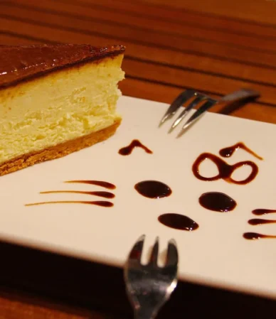 Slice of baked cheesecake with a caramel top and chocolate drizzle on a white plate, similar to this turtle cheesecake