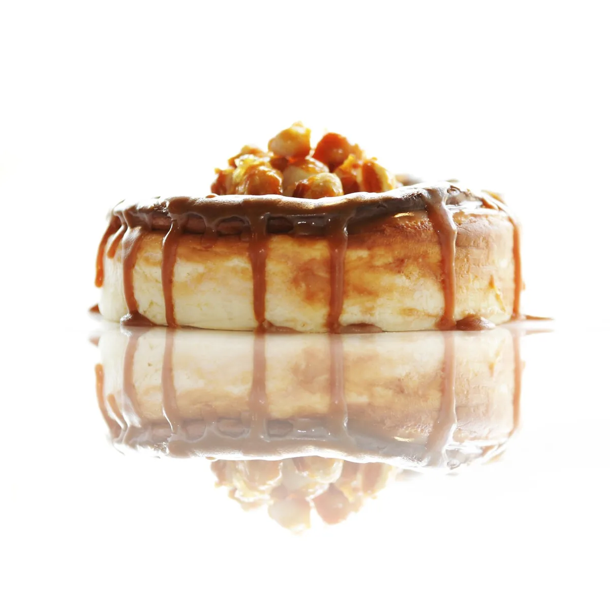 Small cheesecake with caramel dripping down the sides and nuts on top, similar to a turtle cheesecake recipe