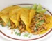 Four shredded chicken tacos in corn tortillas with cilantro and lime wedges, similar to these crockpot chicken tacos
