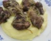 Beef liver and onions served over mashed potatoes on a blue and white plate