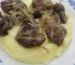 Beef liver and onions served over mashed potatoes on a blue and white plate