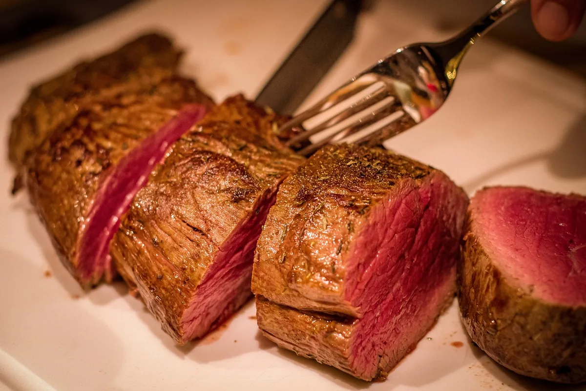 Sliced medium-rare steak with a browned crust, similar to the steak in this steak and potatoes recipe