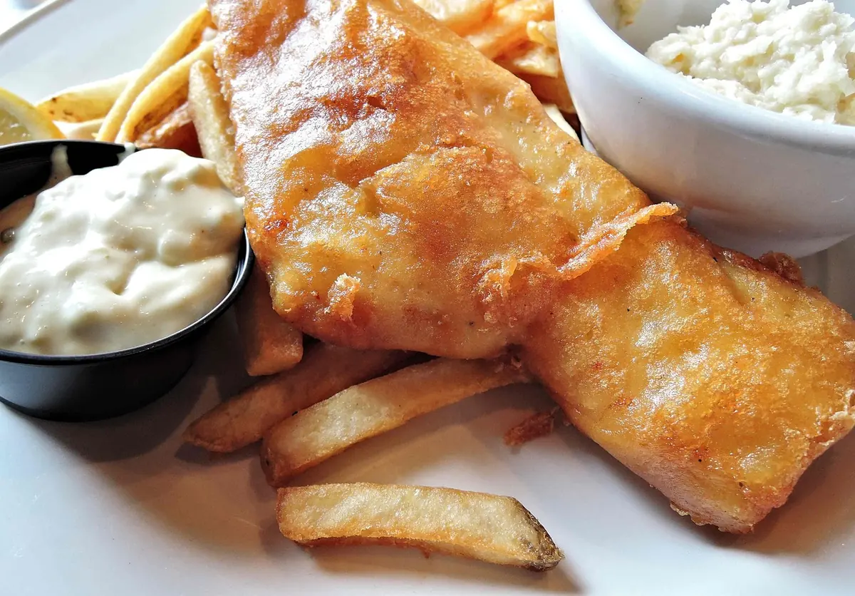 Tartar sauce in a ramekin beside battered fish and fries, one of the sauces for crab cakes