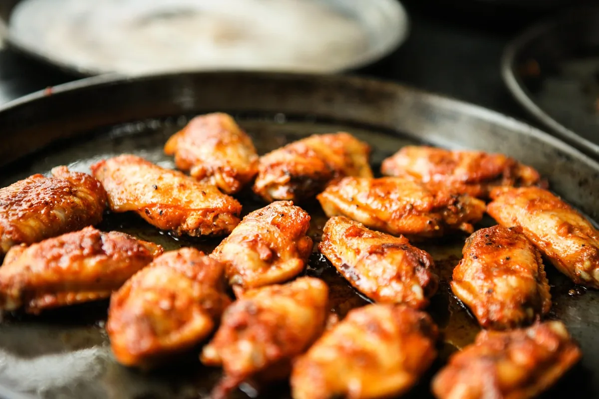 Chicken wings coated in a red chicken wing dry rub browning in a pan