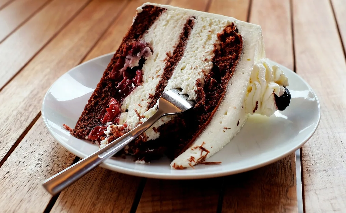 Slice of chocolate layer cake with white cream filling on a plate, similar to a cookies and cream cake slice