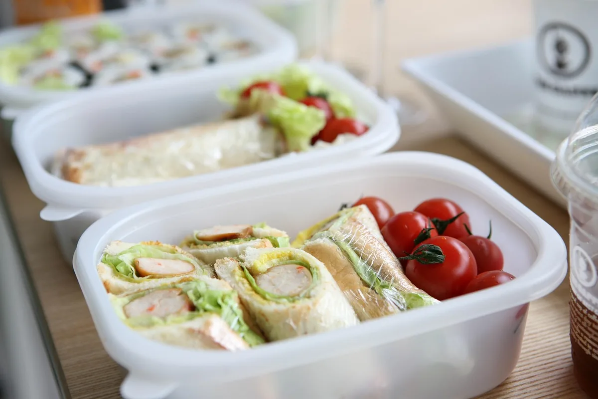 Lunch containers packed with wraps and cherry tomatoes, an easy way to meal prep chicken salad