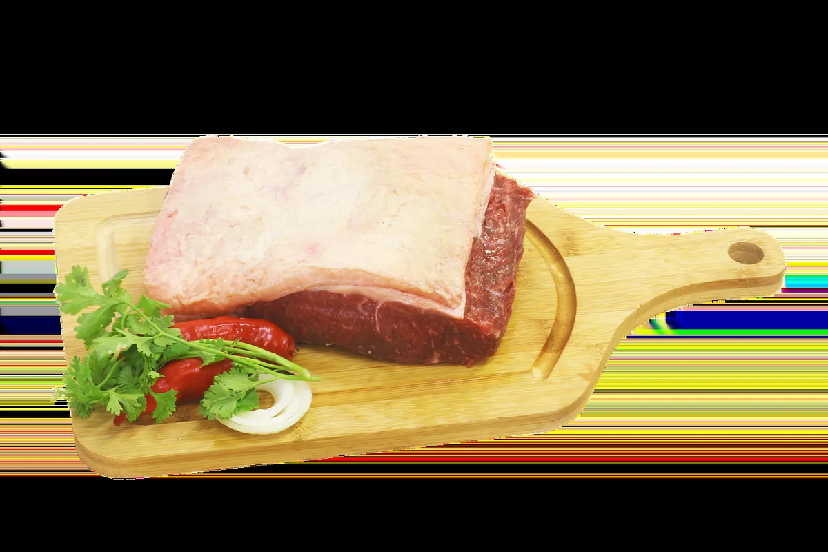 Raw beef brisket with a fat cap on a wooden board, the cut used for corned beef