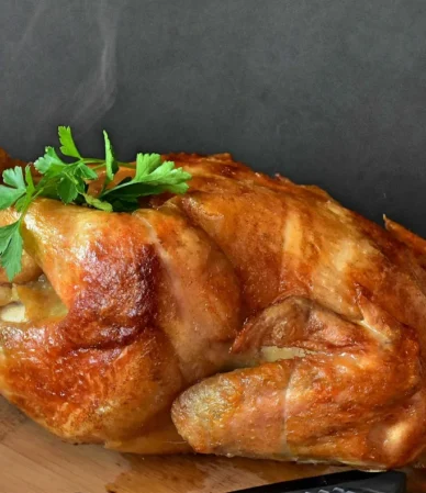 Golden roast chicken with parsley on a wooden board, juicy after a chicken brine