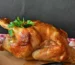 Golden roast chicken with parsley on a wooden board, juicy after a chicken brine