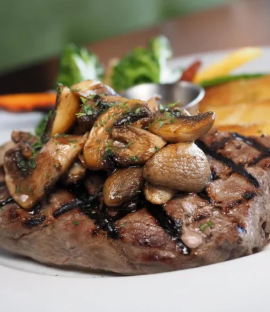 Grilled sirloin steak topped with sautéed mushrooms on a plate, like a petite sirloin steak dinner
