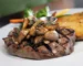 Grilled sirloin steak topped with sautéed mushrooms on a plate, like a petite sirloin steak dinner