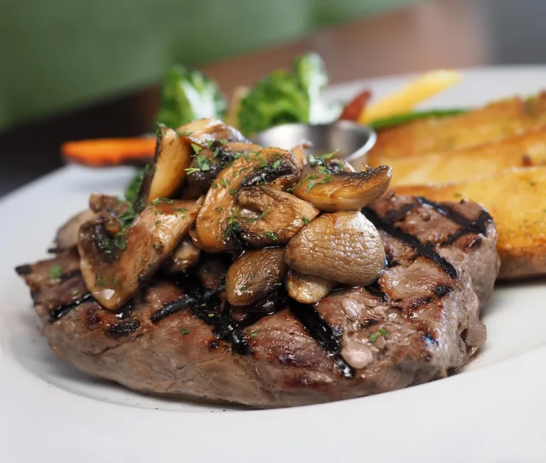 Grilled sirloin steak topped with sautéed mushrooms on a plate, like a petite sirloin steak dinner