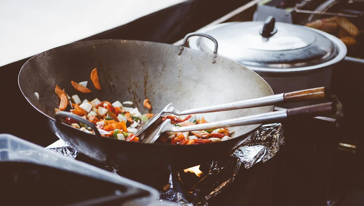 Vegetables being stir-fried in a large wok on a stove
