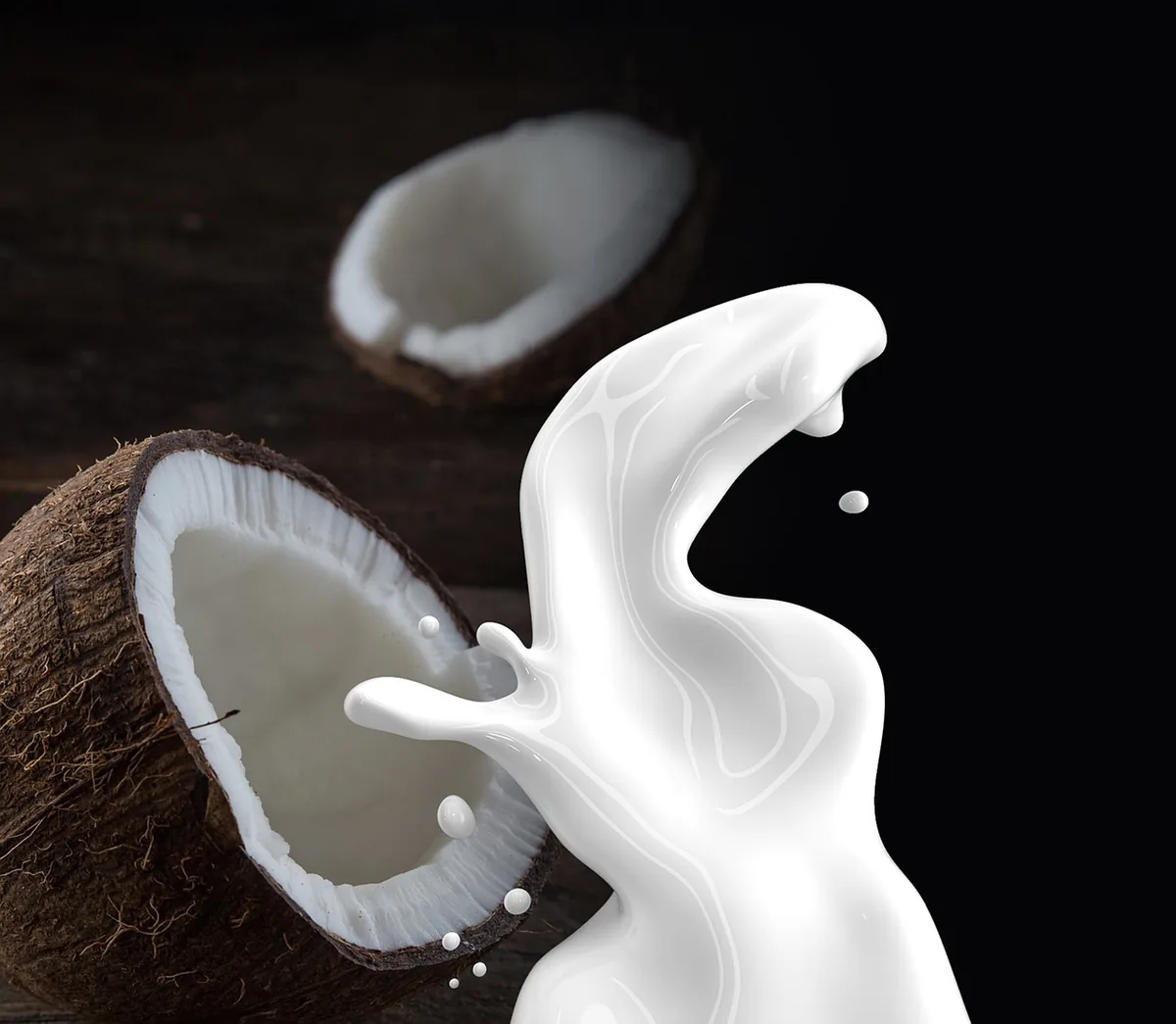 Glass of coconut milk next to a halved coconut