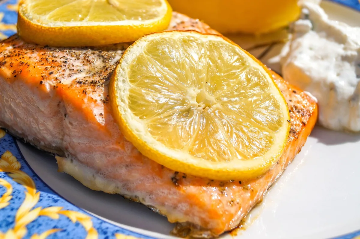 Baked salmon fillet topped with lemon slices, served with a creamy dip