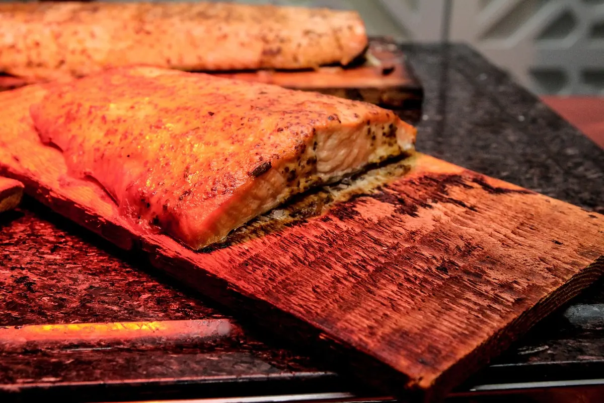 Cooked salmon fillets on charred cedar planks