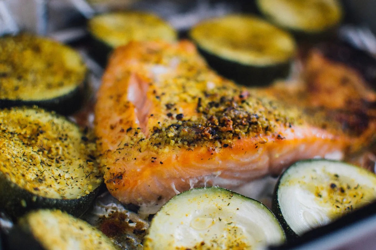 Herb-seasoned salmon fillet roasting with zucchini slices