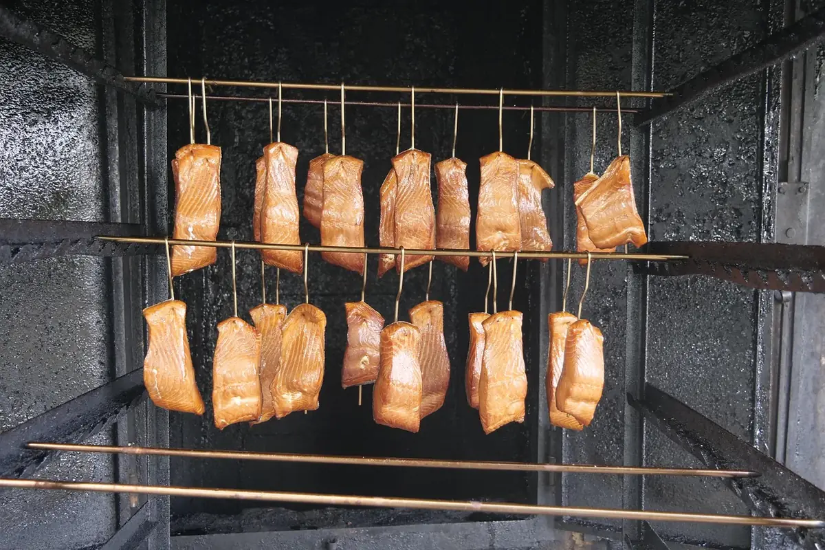 Pieces of fish hanging on rods inside a smokehouse