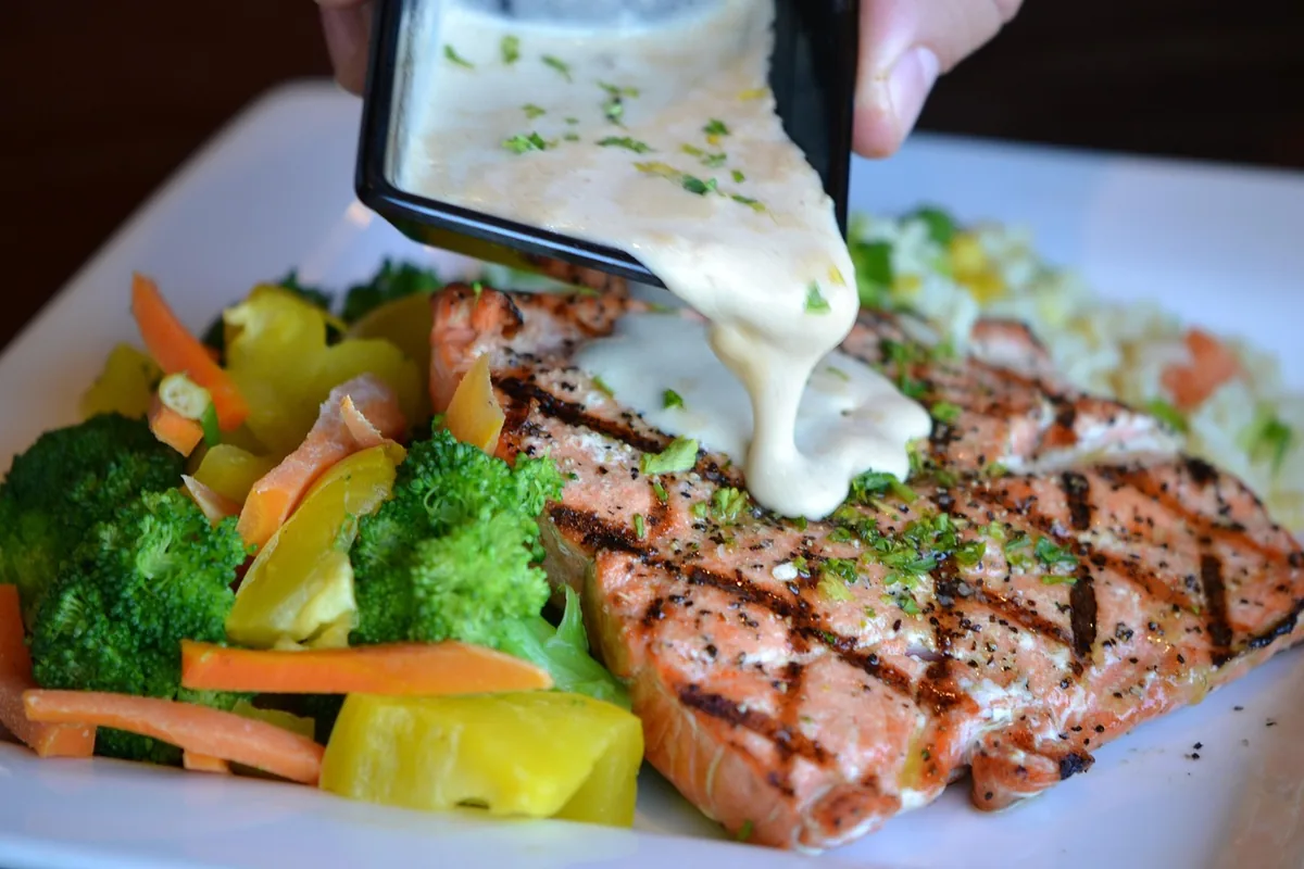 Grilled salmon fillet with broccoli, carrots and a grain side, similar to a salmon quinoa plate