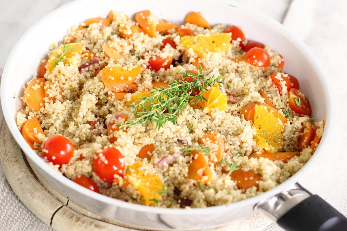 Quinoa with cherry tomatoes, roasted squash and thyme in a white skillet, one of these easy quinoa recipes