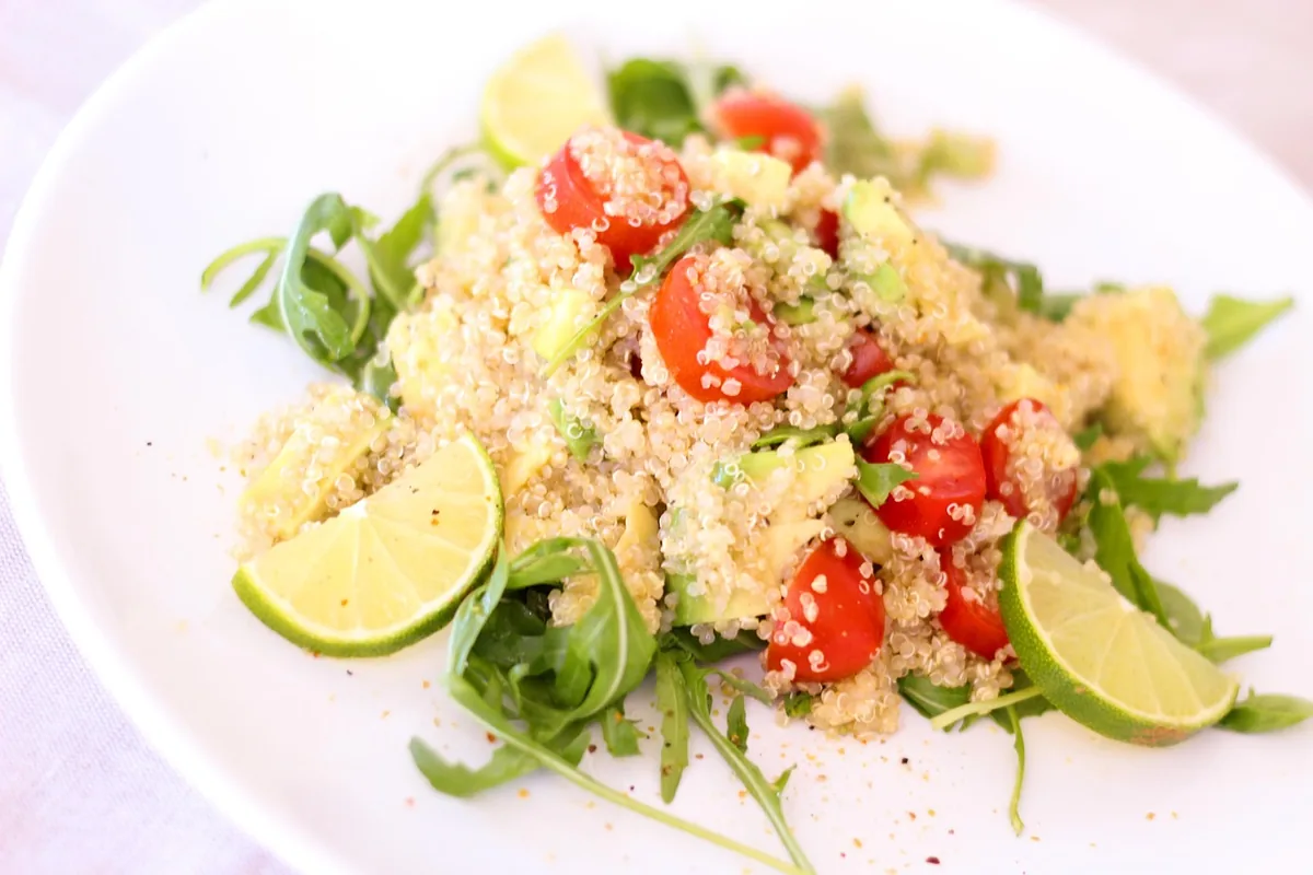 Quinoa salad with cherry tomatoes, arugula and lime wedges
