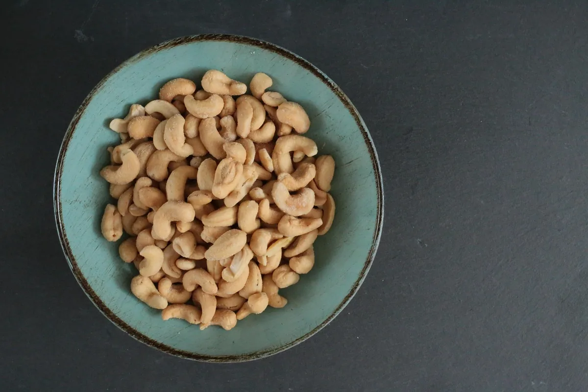 Raw cashew nuts in a blue ceramic bowl, used to make a creamy butter masala sauce